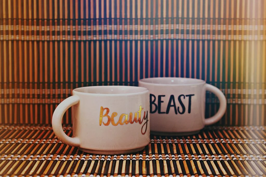Charming Beauty and Beast mugs set against a colorful bamboo backdrop.