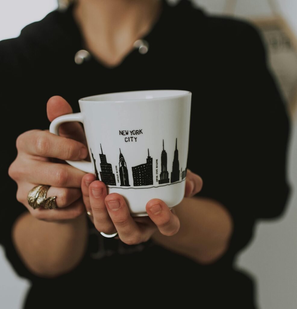Close-up of a woman holding a coffee mug with New York City skyline design.